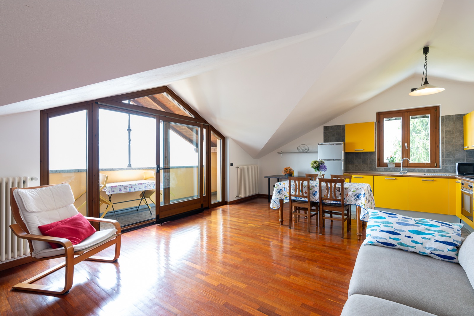 Wohnzimmer im Dachgeschoss mit gelber Küche und Ausgang zur Terrasse