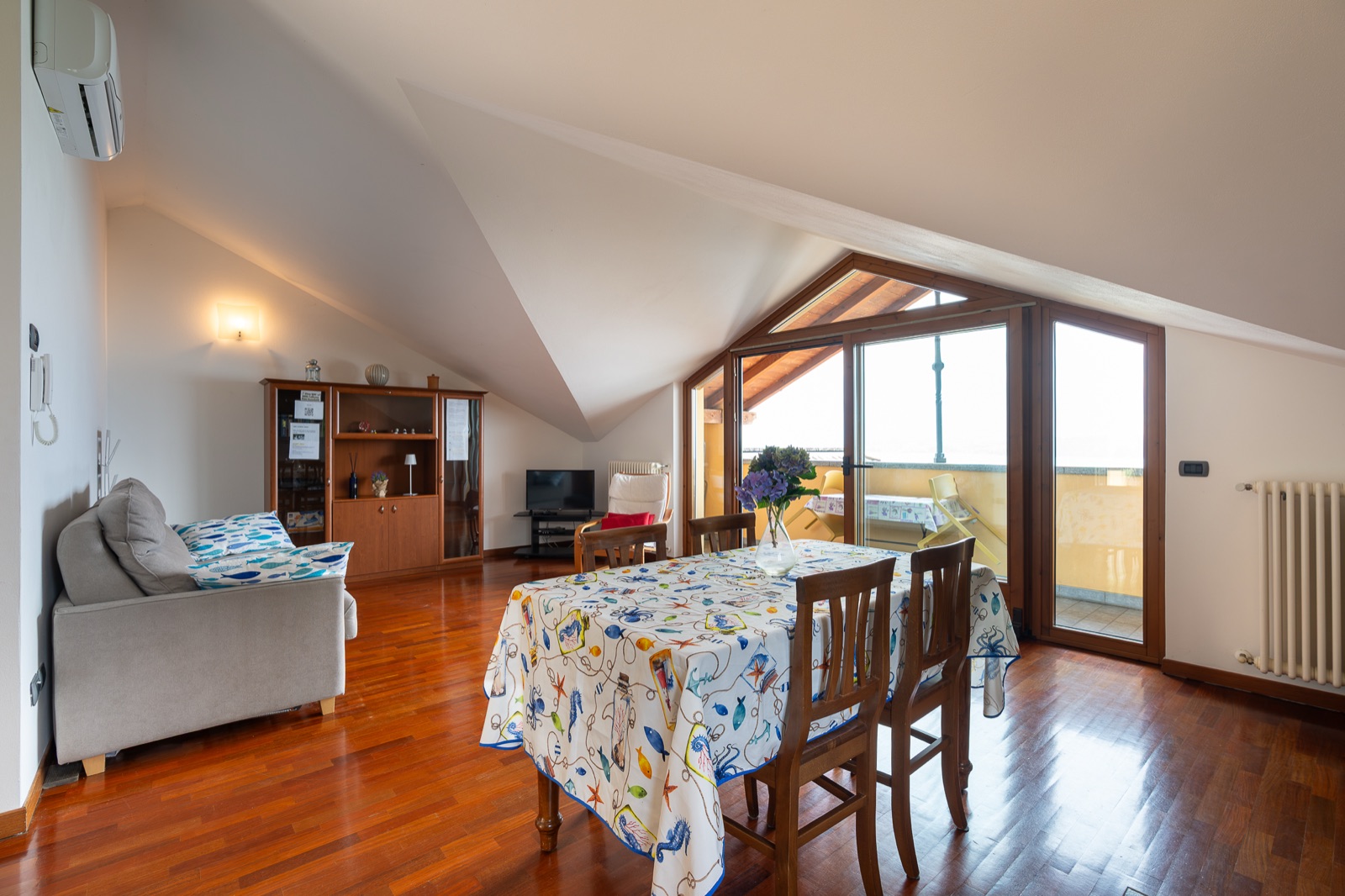 Helles Wohnzimmer mit Glastüren zur Terrasse und Blick auf den See