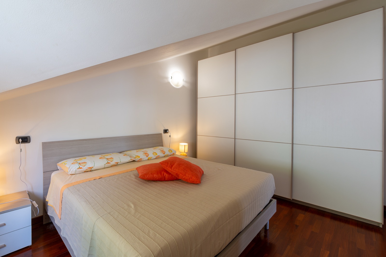 Doppelbett mit orangefarbenen Kissen