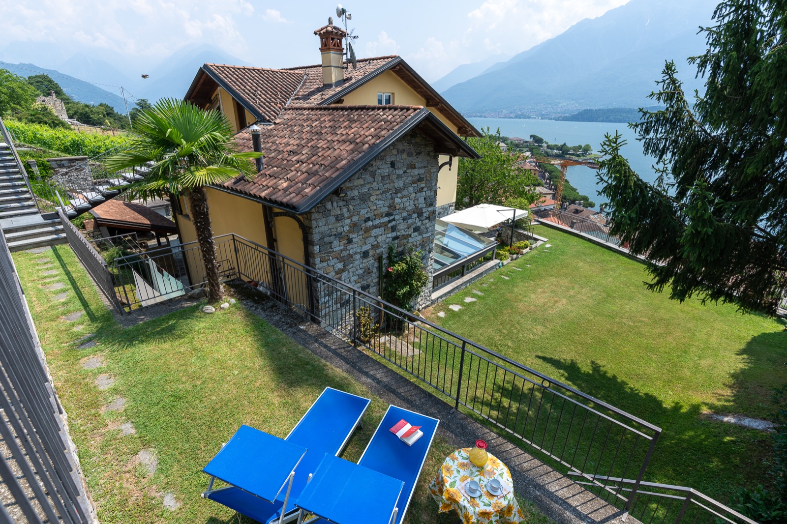 Terrassengarten mit blauen Sonnenliegen und dem Comer See von oben