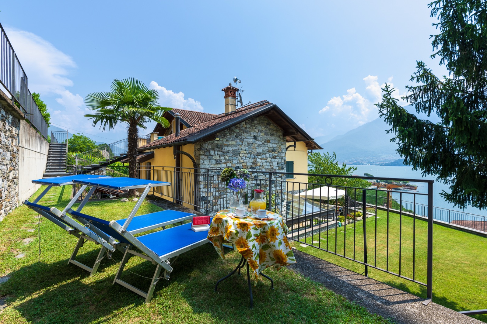 Garten mit blauen Sonnenliegen und Frühstück mit Seeblick